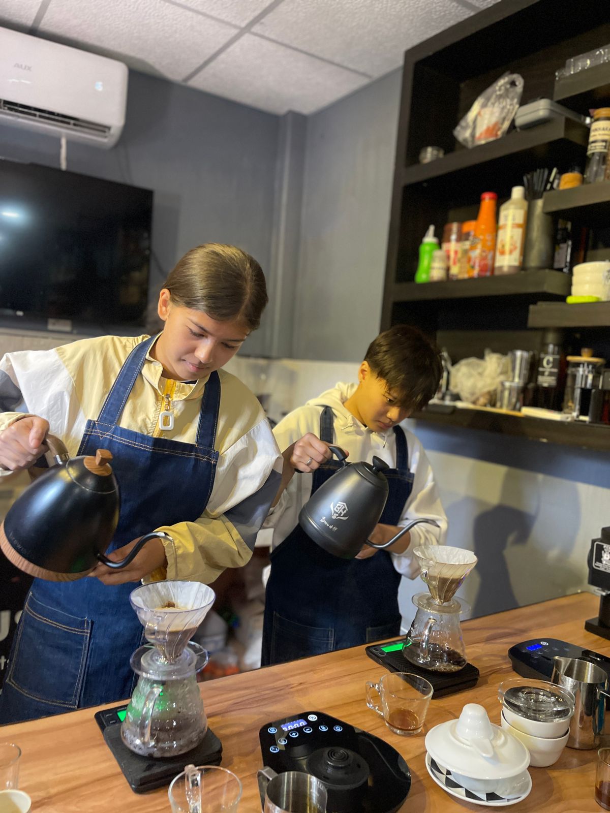 Hand pouring coffee from a glass pitcher into a glass cup